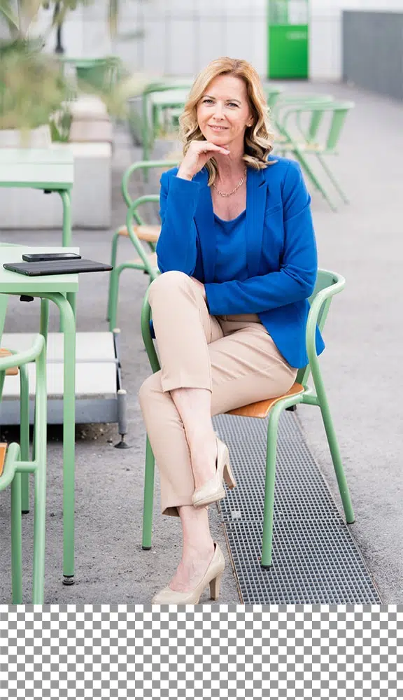 Blonde Frau in einem strahlend Blauen Blazer sitzt auf einem grpnen Cafésessel